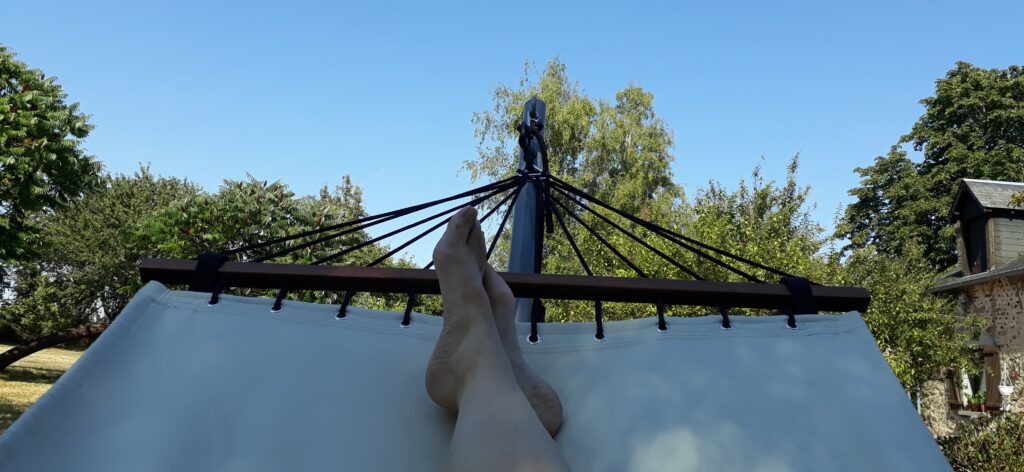 Deze foto drukt ontspanning uit: twee voeten in een hangmat waarboven bomen uitsteken